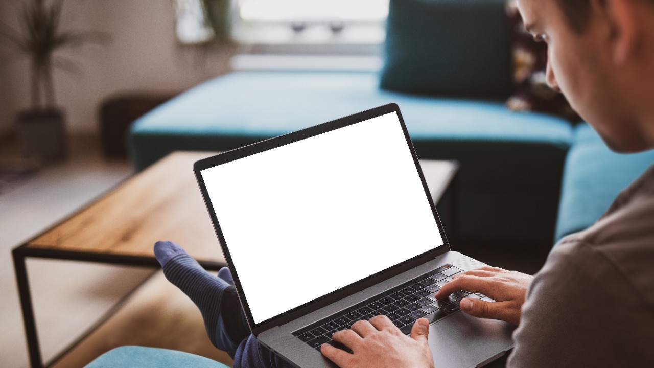 Man using laptop blank screen while sitting on sofa